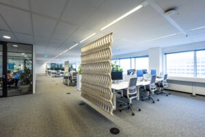 Moderne kantoortuin aan de Johan Huizingalaan met open werkplekken, glazen vergaderruimte en een opvallend decoratief scheidingselement.